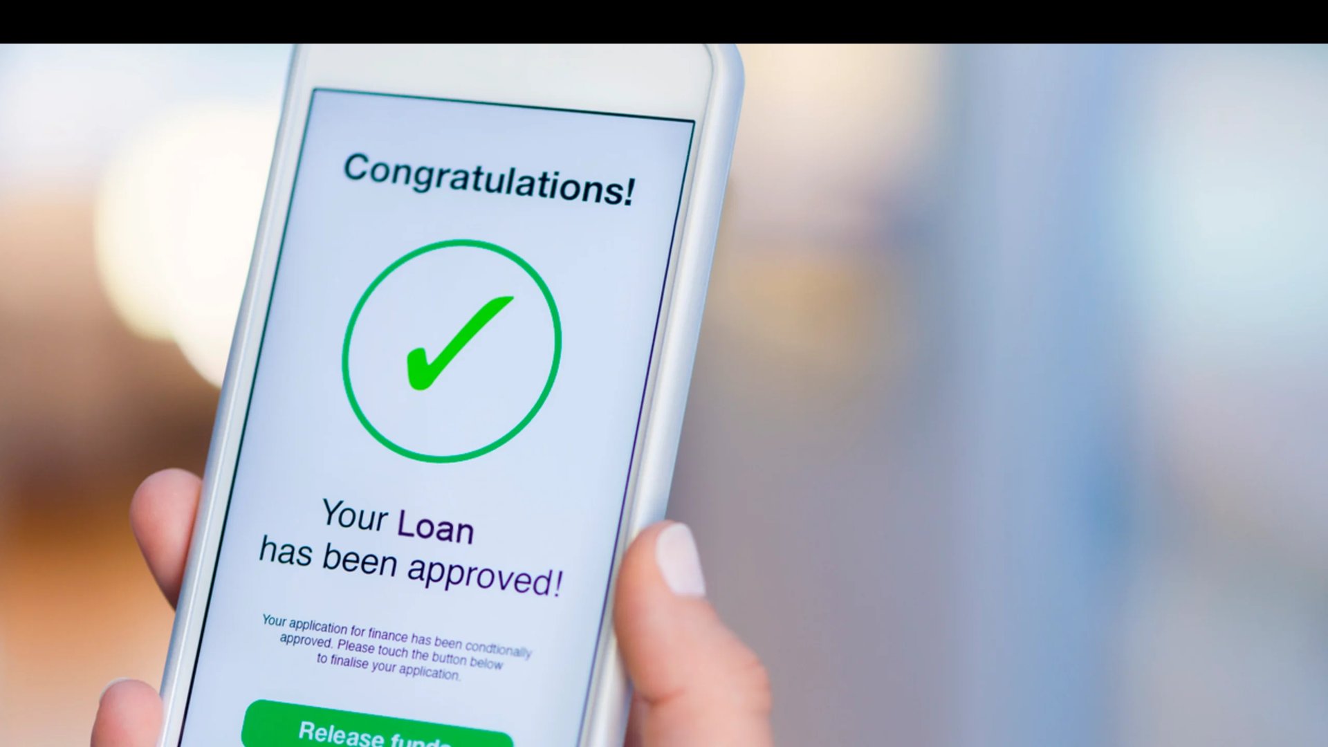 Hand holding smartphone displaying loan approval notification with green checkmark and congratulations message