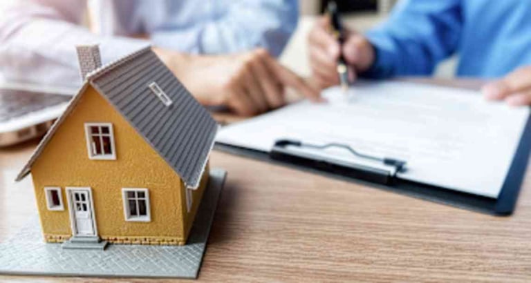Miniature yellow house model with people reviewing documents