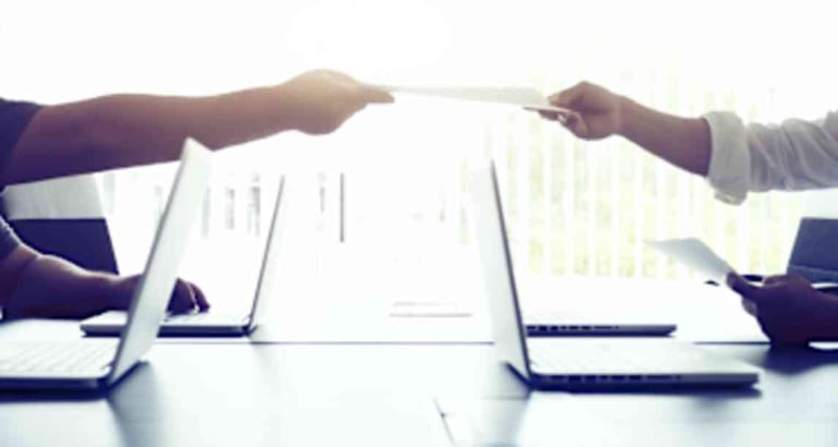 Two people exchanging documents in a business meeting