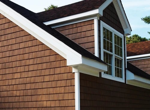 Modern house exterior with brown cedar shake siding, white trim, gabled roof with black shingles, and large windows
